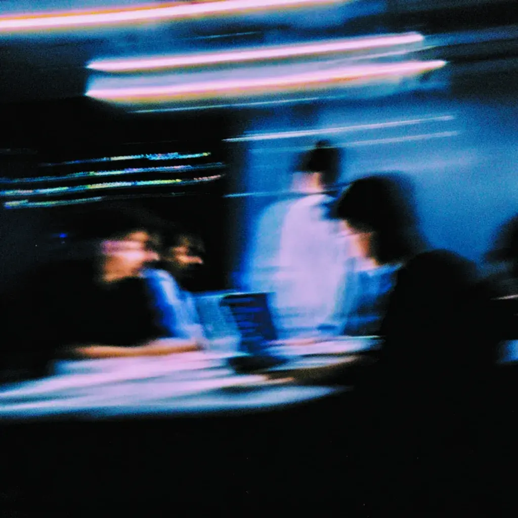 Man wearing white jacket and sunglasses against bright blue background.